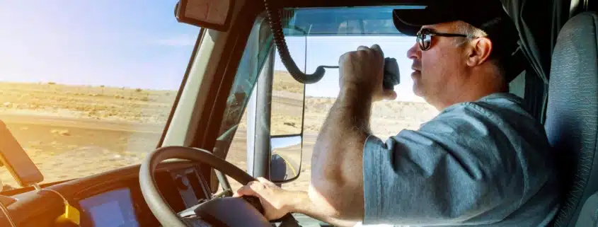 A truck driver driving while talking into his radio